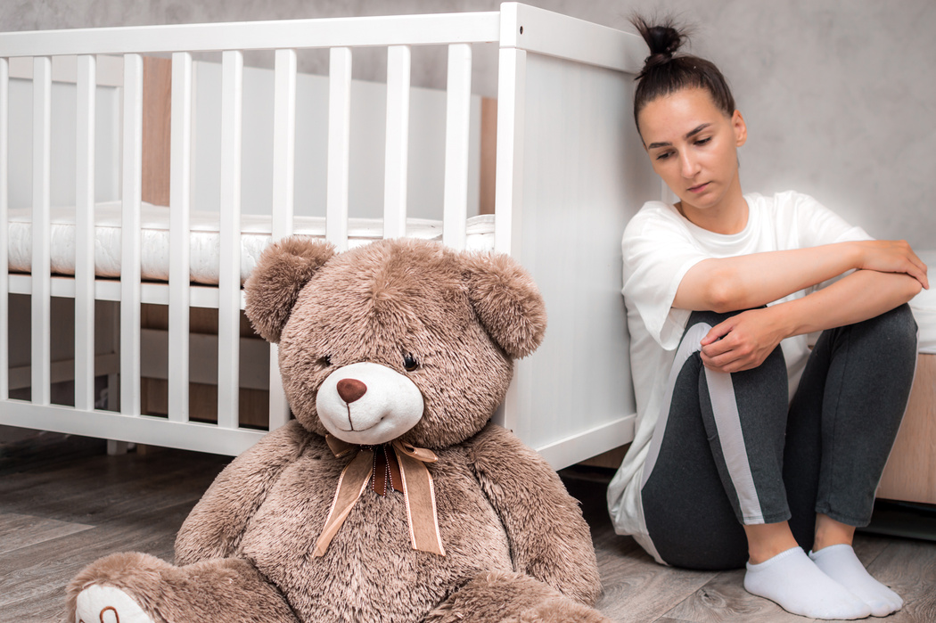 Post Partum Concept with Sad Woman near Crib and Toy